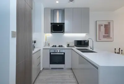 a kitchen with white cabinets and a stove top oven at Waterfront Luxe Haven Peninsula in Dubai