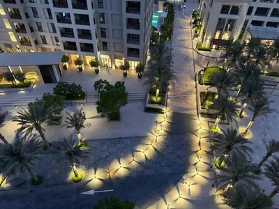 an empty street with palm trees and lights at night at Luxury 1BR I Creek Beach I Pool & Beach in Dubai