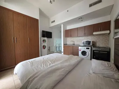 a bedroom with a white bed and a kitchen at Burj Sabah in Dubai