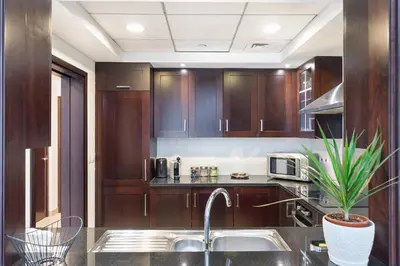 a kitchen with wooden cabinets and a sink at Burj Khalifa District Luxury Apartment - Downtown Dubai in Dubai