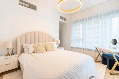 a white bedroom with a large bed and a desk at Burj Khalifa District Luxury Apartment - Downtown Dubai in Dubai