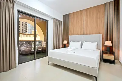 a bedroom with a large white bed and a living room at Spacious 4BR in JBR Steps to Beach & Walk in Dubai