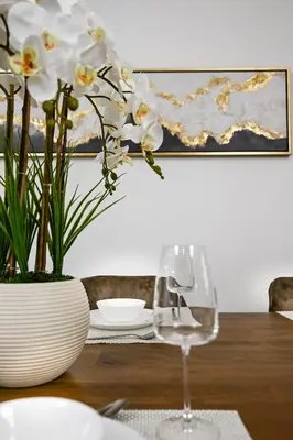 a table with a wine glass and a vase with flowers at Spacious 4BR in JBR Steps to Beach & Walk in Dubai