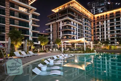 a pool with chairs and an umbrella in front of a building at Burj Khalifa View from Roof-Pool & Gym -Parking in Dubai