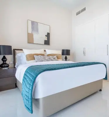 a white bedroom with a large bed and two lamps at Luxury Living In JVC in Dubai