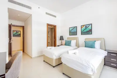 two beds in a hotel room with white walls at Golf Promenade 2-B, Damac Hills - 2BR Apartment - Allsopp & Allsopp in Dubai