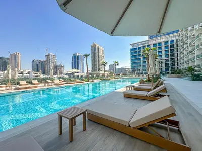 a pool with chairs and a table next to a building at WelHome - Perfect Cozy Studio with Pool, Gym & Balcony in Dubai