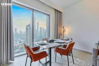 a dining room with a table and chairs and a large window at bnbmehomes - Downtown Views II - Tower 1 in Dubai