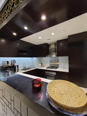 a kitchen with black and white cabinets and a table at Downtown Dubai Burj Khalifa View 2 BHK Dubai Mall in Dubai