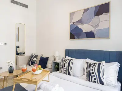a living room with a bed and a table at Livin' Holidays - Studio - Azizi Lovely Studio in Dubai