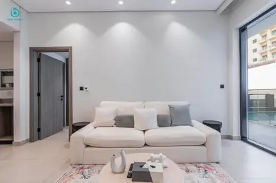 a living room with a white couch and a table at Blue Breeze - Stylish 1 BR in JVC Al Serh Residence in Dubai