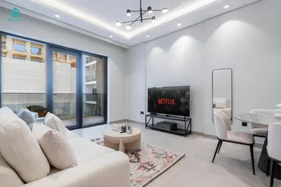 a living room with a white couch and a tv at Blue Breeze - Stylish 1 BR in JVC Al Serh Residence in Dubai