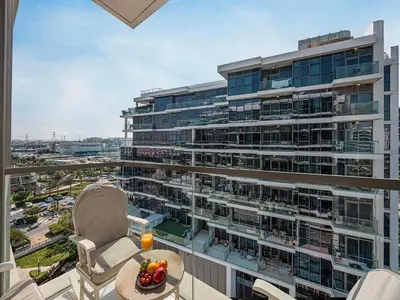 a balcony with a large building with a table and chairs at Livin' Holidays - 1 BR - Elegant Apartment in Dubai