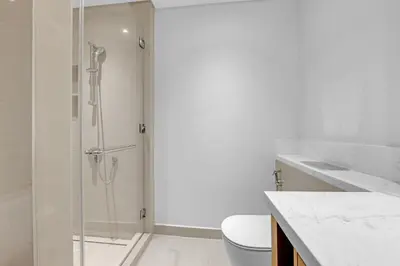 a bathroom with a shower with a toilet and a sink at Neat 3BR Habour Views with Balcony-Burj Khalifa View, Pool, Gym and Modern Facilities in Dubai