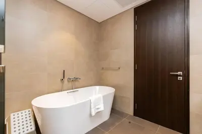 a bathroom with a white tub and a brown door at CitiHome - Stunning 5-Star Suite Jumeirah Living in Dubai