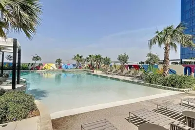 a large swimming pool with chairs and palm trees at 3 bedroom 51st floor Panoramic ocean views in Dubai