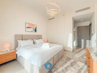 a white bedroom with a large bed and a chandelier at Next to Burj Khalifa - Skyline Balcony Like home in Dubai