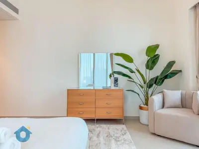 a bedroom with a dresser and a couch and a plant at Best Burj Khalifa Skyline View Huge 3BR Like Home in Dubai