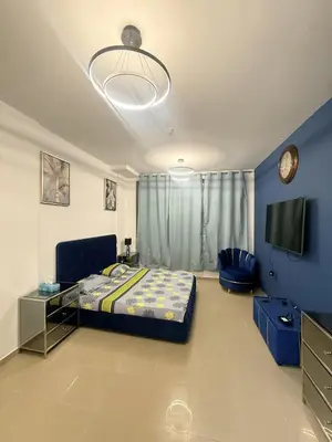 a bedroom with a bed and a tv in it at Cozy Studio Apartment in JCV in Dubai