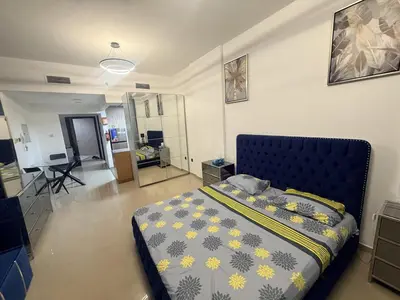 a bedroom with a bed and a living room at Cozy Studio Apartment in JCV in Dubai