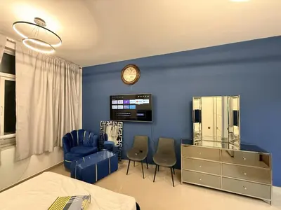 a bedroom with a bed and chairs and a clock at Cozy Studio Apartment in JCV in Dubai