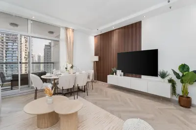 a living room with a dining table and a flat screen tv at Gala Guests - Signature Skyview Tower High-Floor Marina Living in Dubai