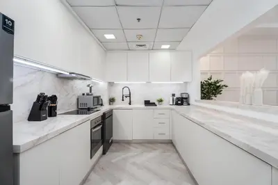 a white kitchen with white counters and appliances at Gala Guests - Signature Skyview Tower High-Floor Marina Living in Dubai