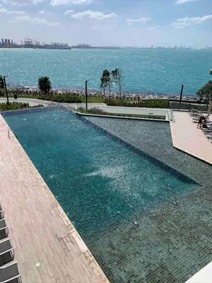 a swimming pool with the ocean in the background at StayShort - Bluewaters Finest Elegant 1BR Apartment - Beach Lifestyle in Dubai