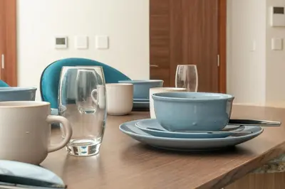 a wooden table with plates and cups and glasses at Imperial Avenue Downtown Lux 1Bed with Balcony in Dubai