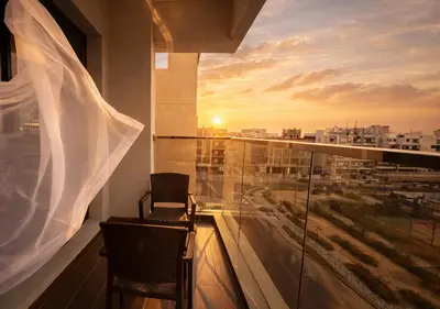 a balcony with a view of a city at sunset at Stylish & Cozy 2BR Apartment in Liwan 2 in Dubai