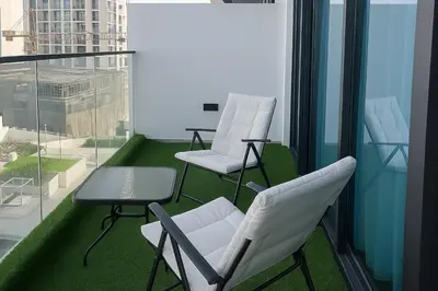 two white chairs and a table on a balcony at Cozy 1-Bedroom Flat in Central JVC in Dubai