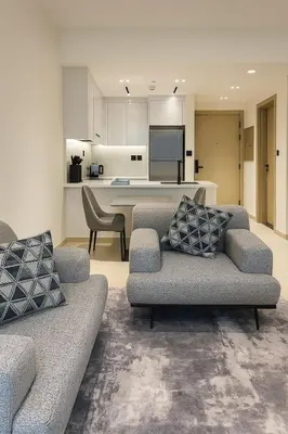 a living room with two couches and a kitchen at Cozy 1-Bedroom Flat in Central JVC in Dubai
