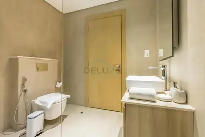 a bathroom with a toilet and a sink and a door at Balcony-Facing Pool 2BR with Assistant Room, Minutes Walk to Park, Miracle and Butterfly Garden, Divine Living, Arjan by Deluxe Holiday Homes in Dubai
