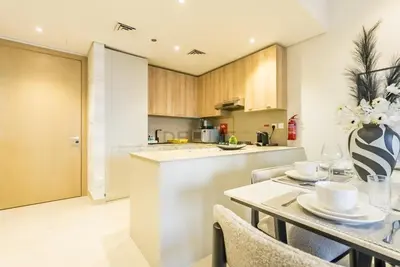 a kitchen and dining room with a table and chairs at Balcony-Facing Pool 2BR with Assistant Room, Minutes Walk to Park, Miracle and Butterfly Garden, Divine Living, Arjan by Deluxe Holiday Homes in Dubai