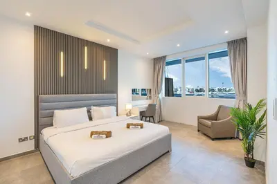 a bedroom with a large white bed and a chair at Palm Home next to Nakheel Mall with Private Beach in Dubai