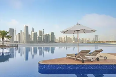 a pair of chairs and an umbrella next to a pool at Palm Home next to Nakheel Mall with Private Beach in Dubai