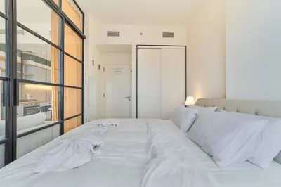 a white bed in a room with a large window at Chic & Modern 1BR Stay in Collective Dubai Hills in Dubai