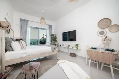 a bedroom with a bed and a table and a tv at HiGuests - Charming Studio with Lake Views in Business Bay in Dubai