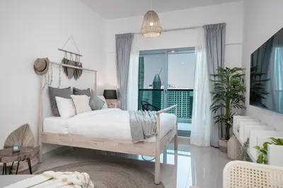 a white bedroom with a bed and a large window at HiGuests - Charming Studio with Lake Views in Business Bay in Dubai