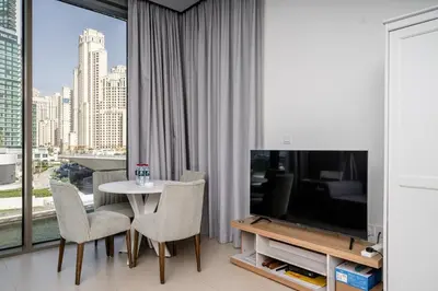 a living room with a television and a table and chairs at Luxury Bluewater Escape 1BR Canal view 5242T in Dubai
