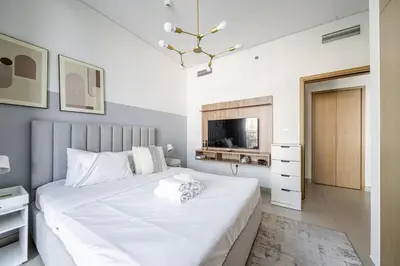 a bedroom with a large white bed and a television at Luxury Bluewater Escape 1BR Canal view 5242T in Dubai