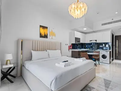 a bedroom with a large white bed and a kitchen at Luxurious Haven Studio In Jewelz Arjan 03 in Dubai