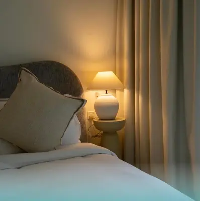 a bedroom with a bed with a lamp and curtains at Luxury Studio With Pool View Near Burj Khalifa in Dubai