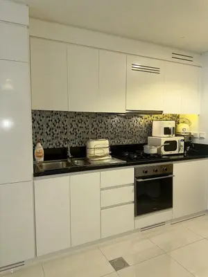 a kitchen with white cabinets and a stove top oven at Luxury Studio With Pool View Near Burj Khalifa in Dubai