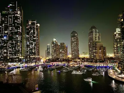 a city skyline at night with boats in the water at Modern 2-Bedrooms Apartment with Stunning Marina Views in Dubai