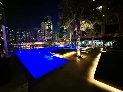 a swimming pool with a city skyline at night at Modern 2-Bedrooms Apartment with Stunning Marina Views in Dubai