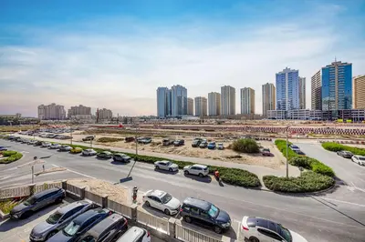 a parking lot with cars parked in front of a city at Daniels Studio at V2 Residence, Sports City in Dubai