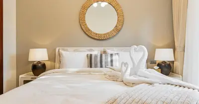 a bedroom with a white bed with a mirror on the wall at Downtown 2BHK Burj View & Private Garden in Dubai