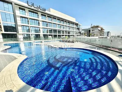 a large swimming pool in front of a building at Inviting Studio Overlooking the Pool, Just a Short Drive from Dubai Autodrome, Samana Golf Avenue, Dubai Studio City by Deluxe Holiday Homes in Dubai