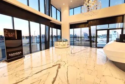 a lobby with a large marble floor and windows at Inviting Studio Overlooking the Pool, Just a Short Drive from Dubai Autodrome, Samana Golf Avenue, Dubai Studio City by Deluxe Holiday Homes in Dubai